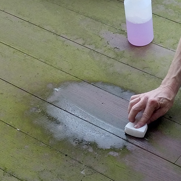 Cleaning wooden deck with sponge to get rid of moss scum.