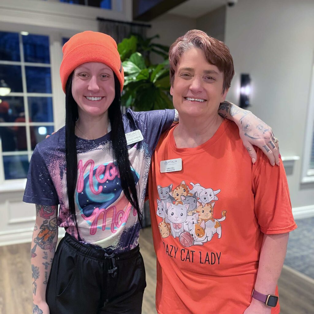 Two women in colorful outfits embrace, smiling, at Vitalia Stow.