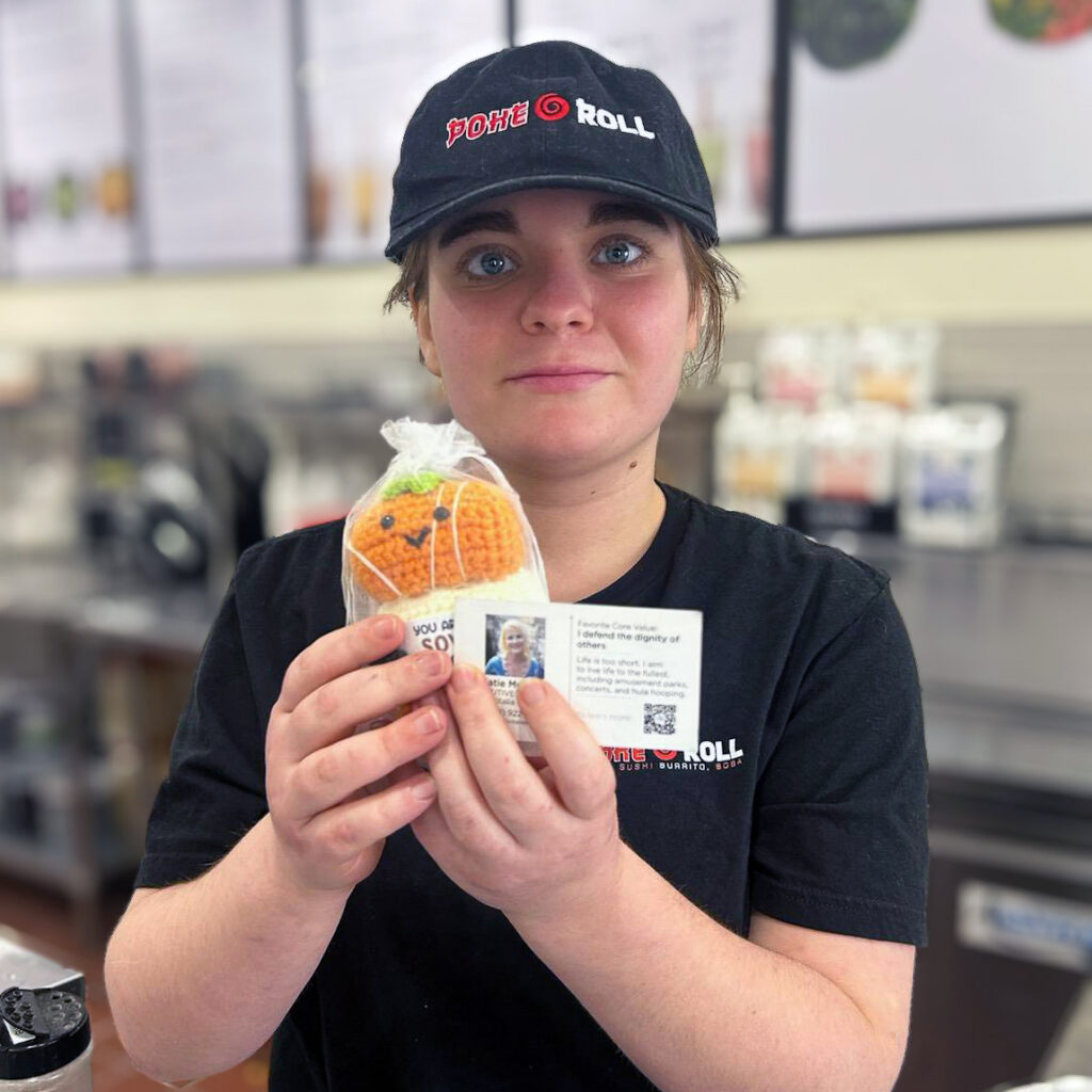 An employee at a local business holds up a gift from Vitalia Stow Senior Residences.