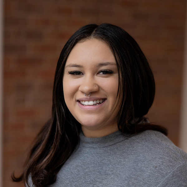 Jayden Graves, Memory Care Director at Vitalia Stow, smiling in a professional headshot, wearing a gray top, with a softly blurred brick background.