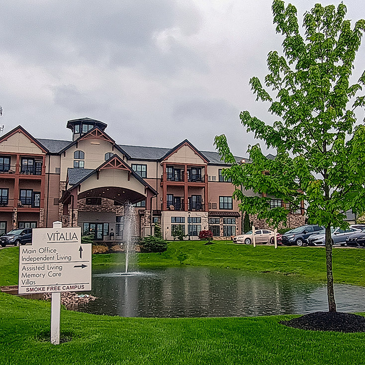 A pond with fountain outside Vitalia Stow, a tree on one side and signpost on the other.
